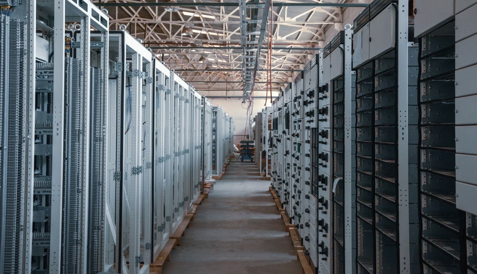 Long aisle between rows of metal server racks in a bright data center