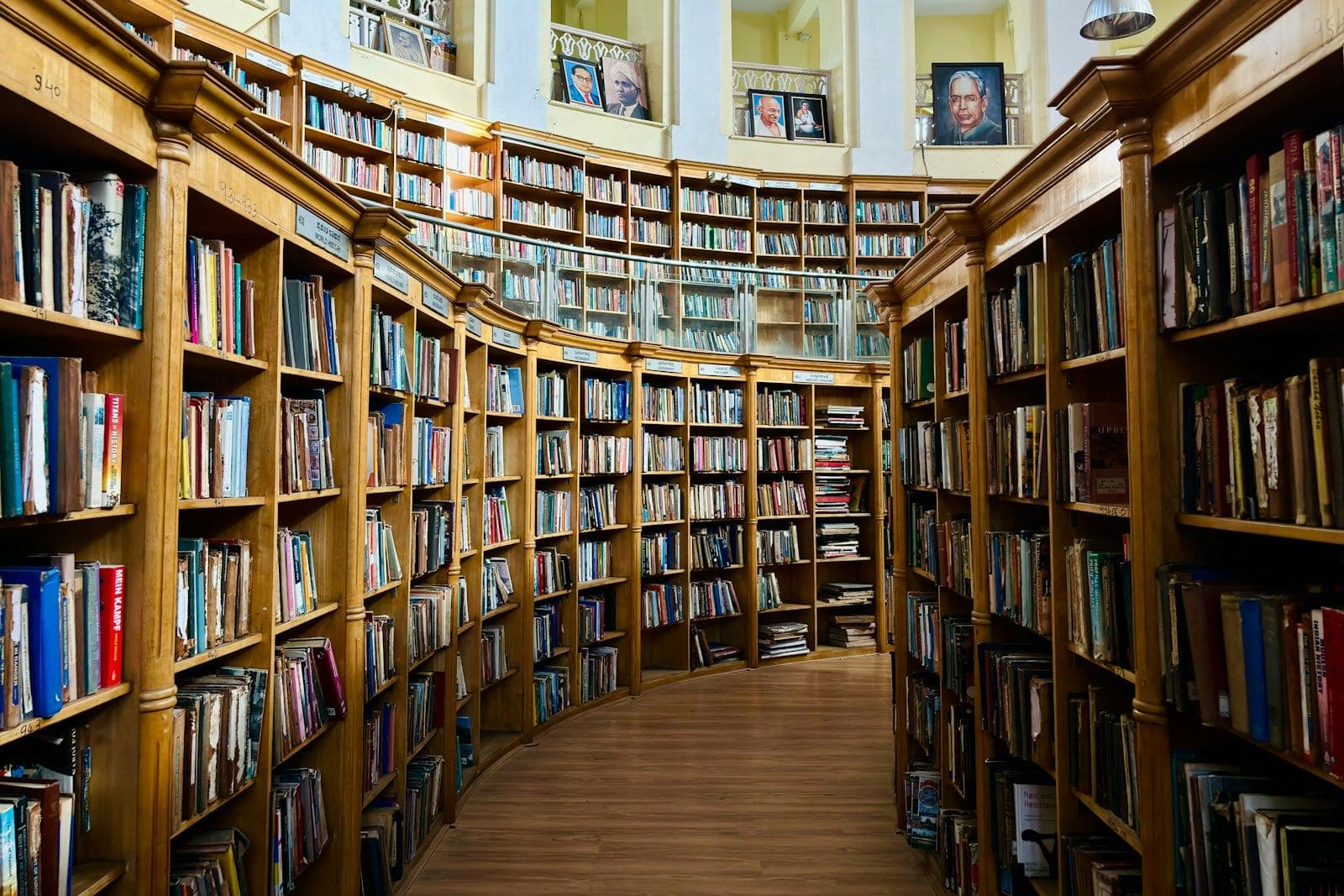Curved wooden library shelves packed with books, with a gallery level above